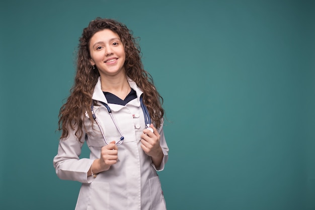 Женщина-врач в белой форме со стетоскопом на зеленом фоне