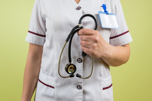 Foto medico femminile in uniforme bianca con uno stetoscopio nel suo primo piano della mano