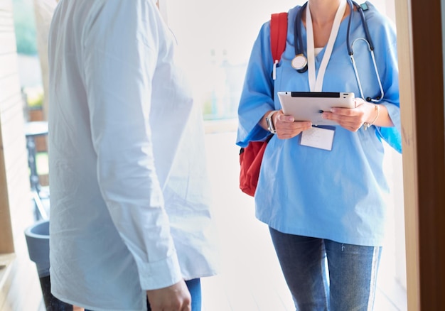 Female doctor with clipboard during home visit while entering house