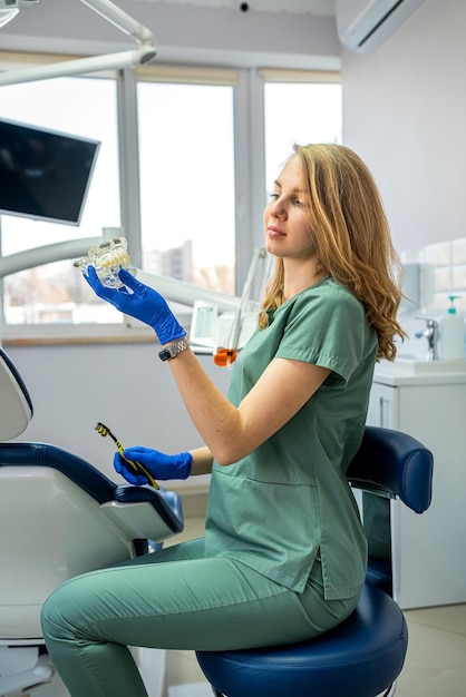 Foto medico femminile con lo strumento nelle sue mani in piedi della moderna clinica dentale medico amichevole