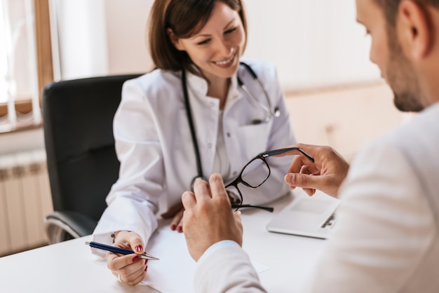 Medico femminile con i rapporti della lettura paziente maschio all'ufficio medico