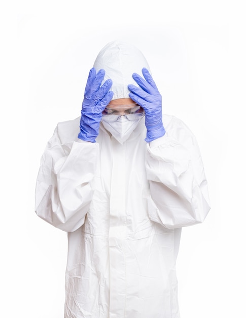 Female doctor with PPE looking at the floor with hands on head on white background