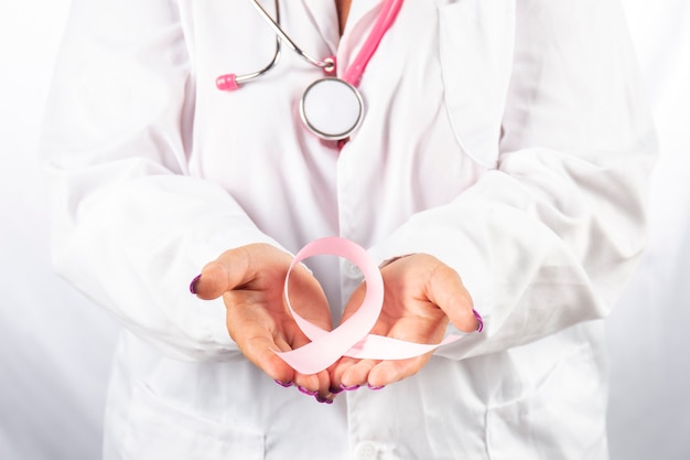 Female doctor with stethoscope holding breast cancer awareness ribbon