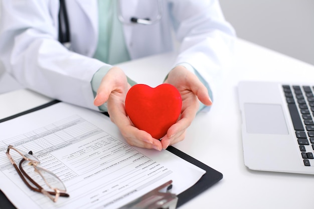 Female doctor with stethoscope holding heart.   Cardio therapeutist, physician make cardiac physical, heart rate measure, arrhythmia, old age life concept