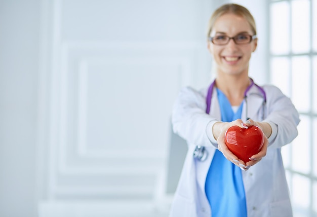 Фото Женщина-врач со стетоскопом держит сердце на руках концепция здравоохранения и кардиологии в медицине