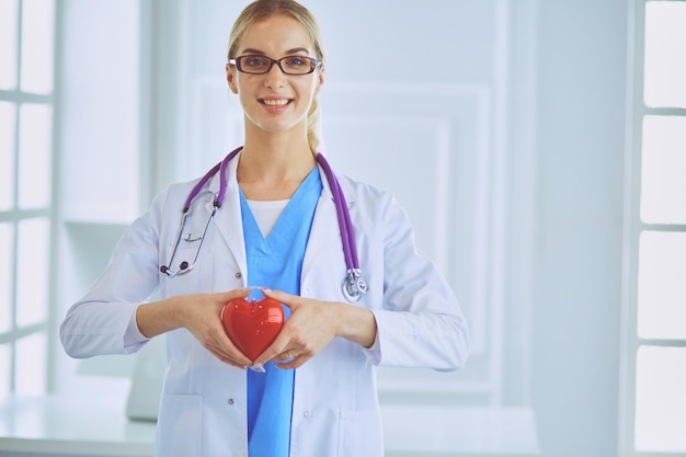 Female doctor with the stethoscope holding heart