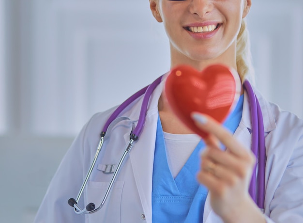 Женщина-врач со стетоскопом, держащим сердце.