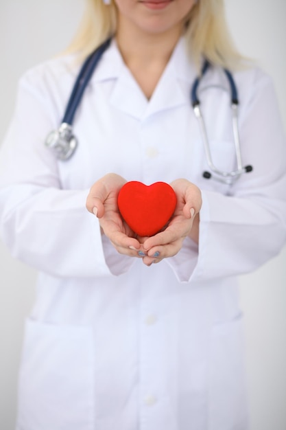 Female doctor with stethoscope holding heart