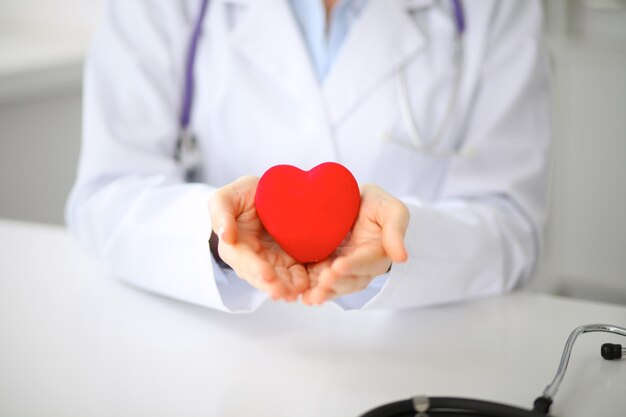 Female doctor with stethoscope holding heart