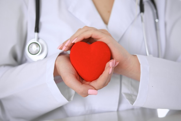 Female doctor with stethoscope holding heart