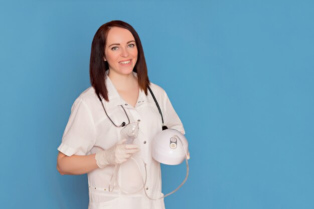 A female doctor with a stethoscope holds an allergic inhaler in her hands. Copy space