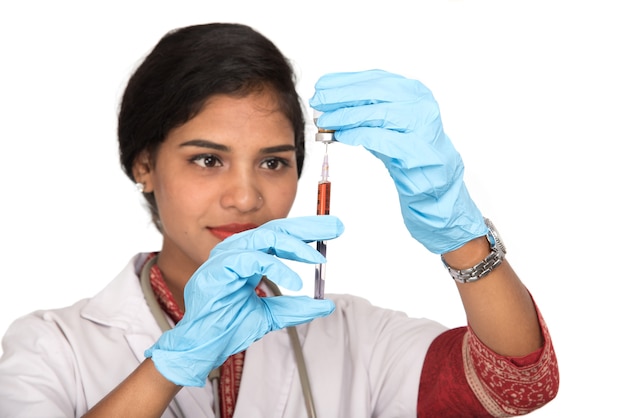 Una dottoressa con uno stetoscopio tiene in mano un'iniezione o una siringa.