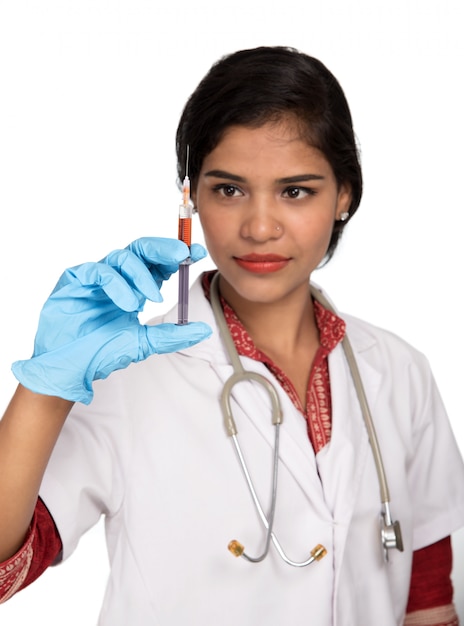 聴診器を持つ女性医師が注射または注射器を持っています。
