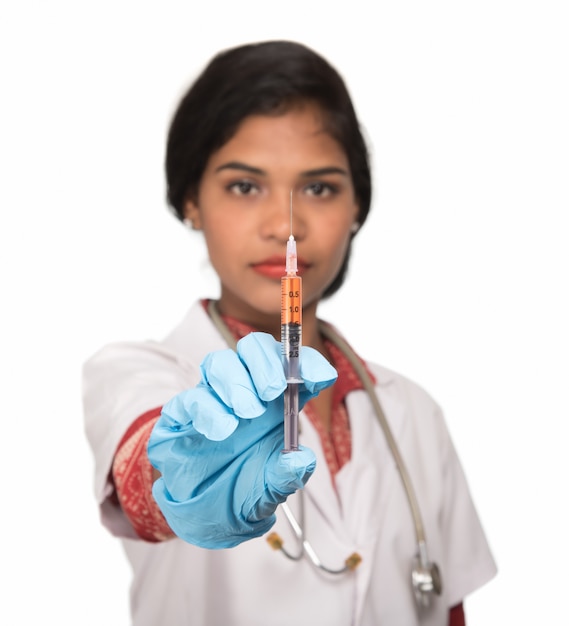 A female doctor with a stethoscope is holding an Injection or Syringe.