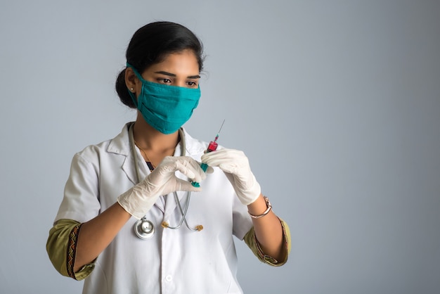 A female doctor with a stethoscope is holding and showing an Injection or Syringe.