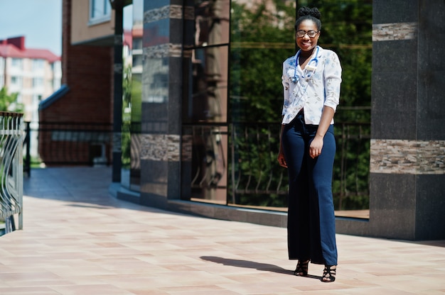 Female doctor with stethoscope posed outdoor against clinic