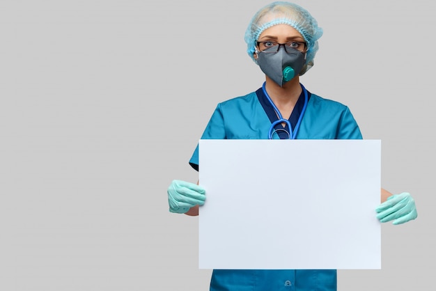 Foto il medico femminile con lo stetoscopio che indossa la maschera protettiva ed i guanti del lattice che tengono lo spazio in bianco firmano sopra la parete grigio chiaro