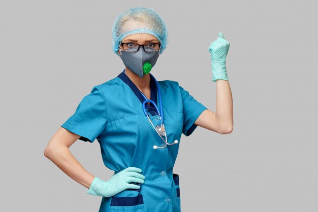 Female doctor with stethoscope wearing protective mask and latex gloves over light grey wall