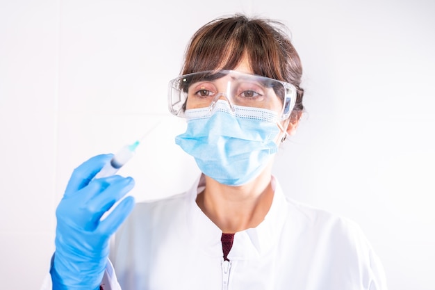 Female doctor with transparent glasses face mask with coronavirus vaccine, antibodies, immunize population.