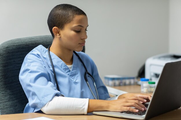 Female doctor working on laptop at desk in hospital