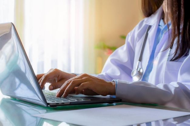 Female doctor working and typing on laptop computer at medical clinic