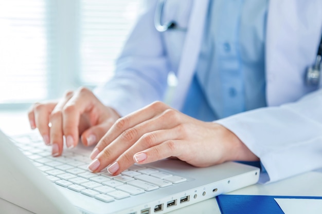 Female doctor working with laptop, close-up