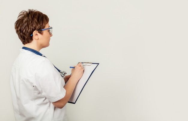 Female doctor writes with a pen a document on a tablet