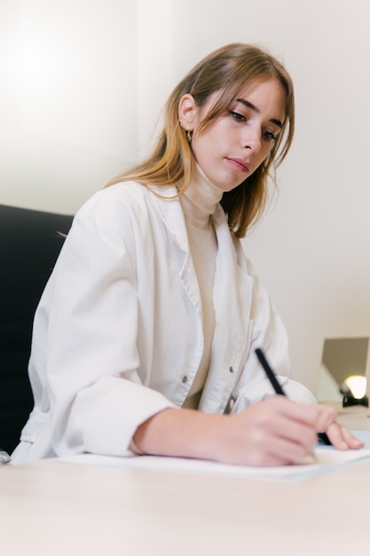 Photo female doctor writing a prescription at her office desk