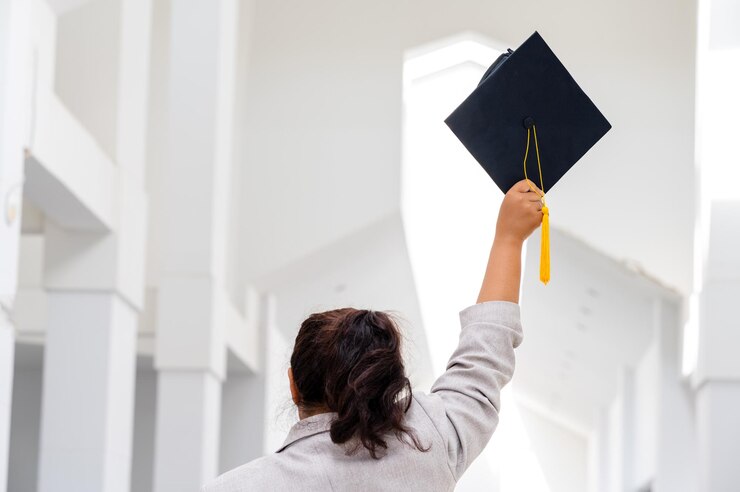Female doctoral graduates wearing yellow tassel black graduation caps are at the university.