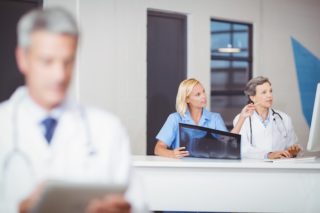 Female doctors with X-ray while working at computer desk