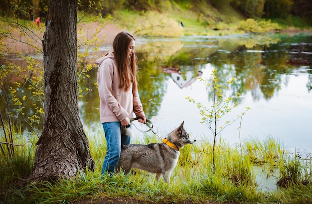 Dog walker femmina con un animale domestico che cammina nella natura lungo il fiume