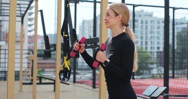 Female doing workout with dumbbells on the the sports ground Physical training Healthy lifestyle Outdoor training