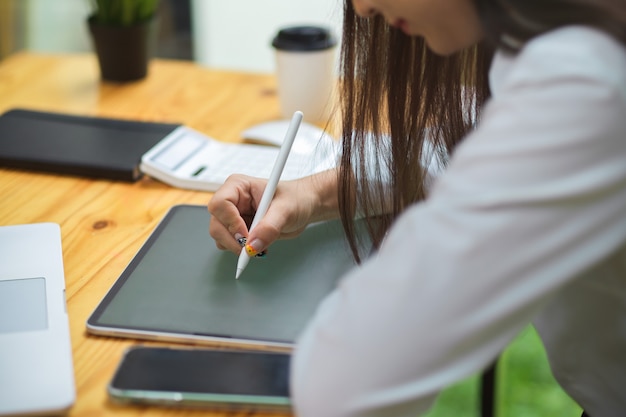 Female drawing on tablet with stylus pen on wooden table at office