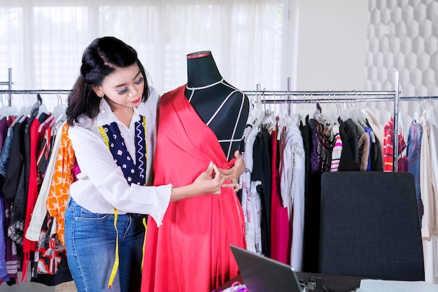 Female dressmaker adjusts a dress on a mannequin