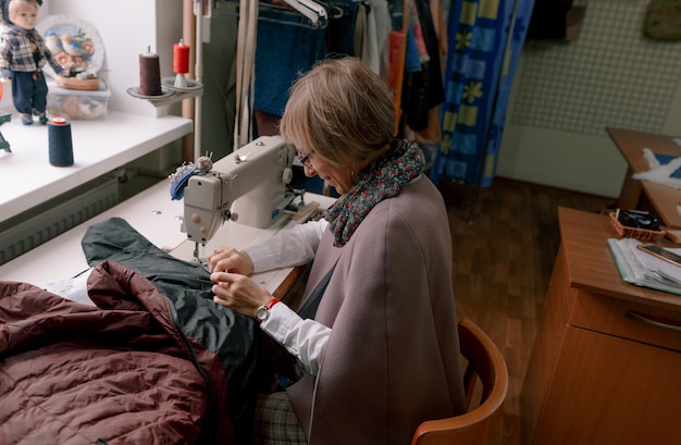 Женщина-портниха использует швейную машинку для создания одежды на заказ в мастерской.