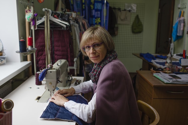 女性の洋裁師がミシンを使って工房でオーダーメイドの服を作る