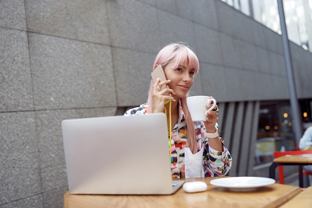 Donna che beve caffè mentre parla sullo smartphone