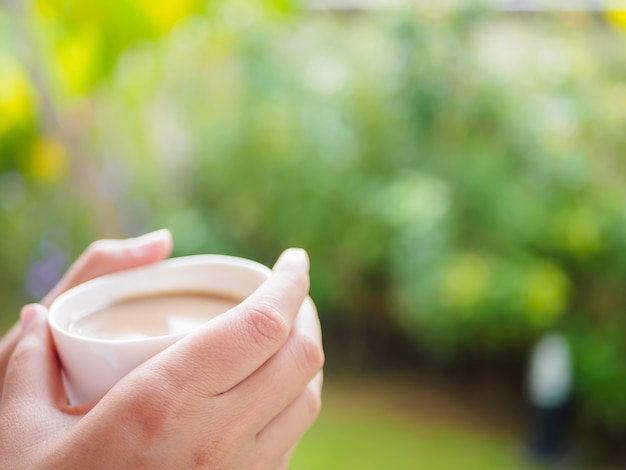 女性、朝、庭でコーヒーを飲む