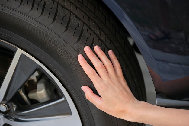 Female driver hands inspecting wheel tire of her new car\
vehicle safety concept