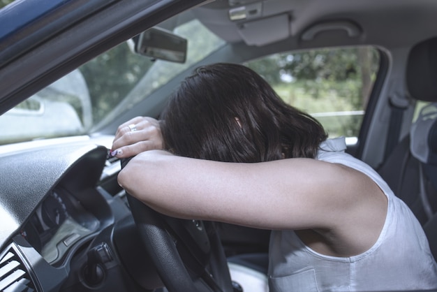a female driver at the wheel falling asleep while driving in a potentially dangerous situation