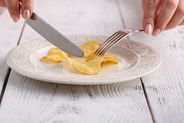 女性は皿にフォークでポテトチップスを食べる