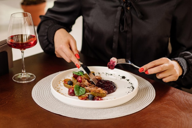 Photo female eating dish with duck and cranberry sauce at the restaurant