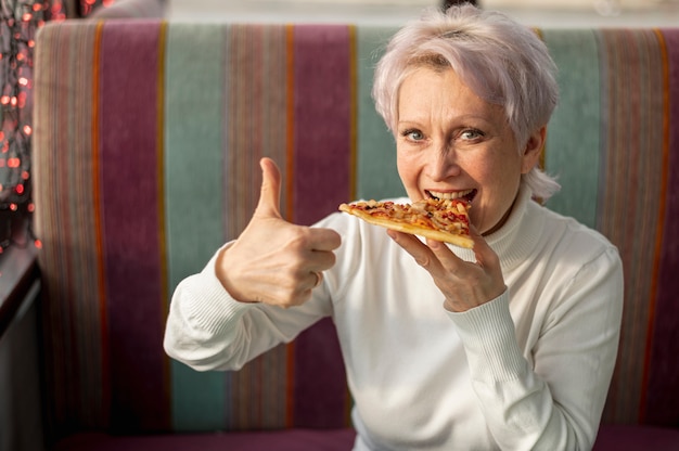 Photo female eating pizza showing ok sign