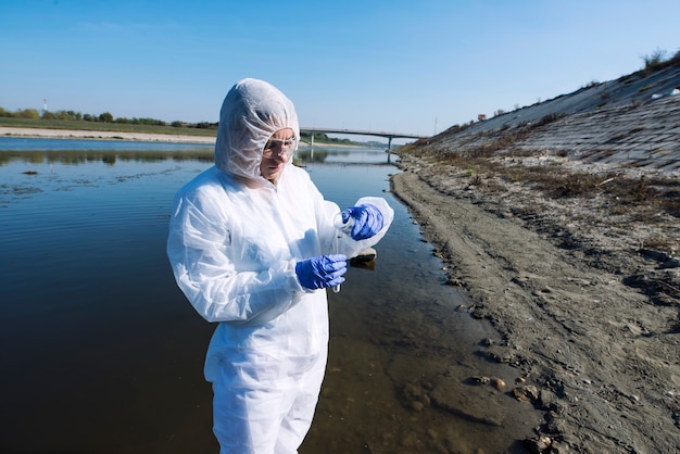 Photo female ecologist expert in protective clothes examining water quality and purity.