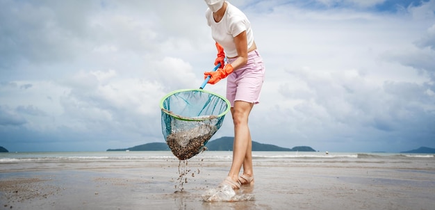 Женщина-волонтер-эколог очищает пляж на берегу моря от пластика и других отходов