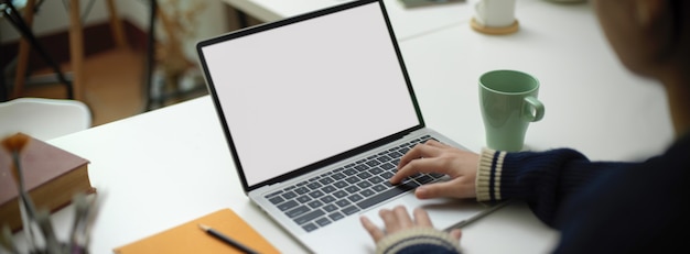 Photo female employee working on  laptop with mug and stationery on portable workspace