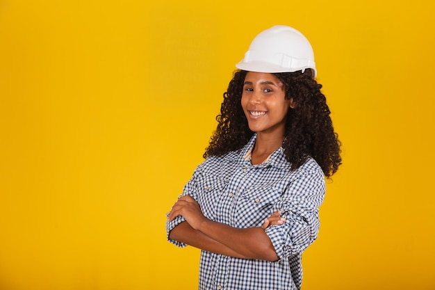 Female engineer or architect on yellow background smiling with arms crossed.