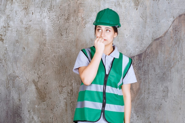 Female engineer in green uniform and helmet looks scared and terrified