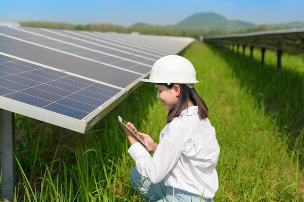 太陽電池ファームまたはソーラーパネルフィールドでヘルメットをかぶった女性エンジニア