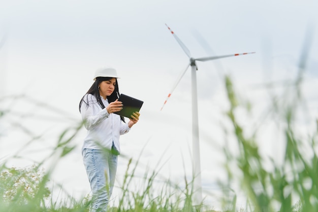 Женщина-инженер в каске работает на ветряной электростанции
